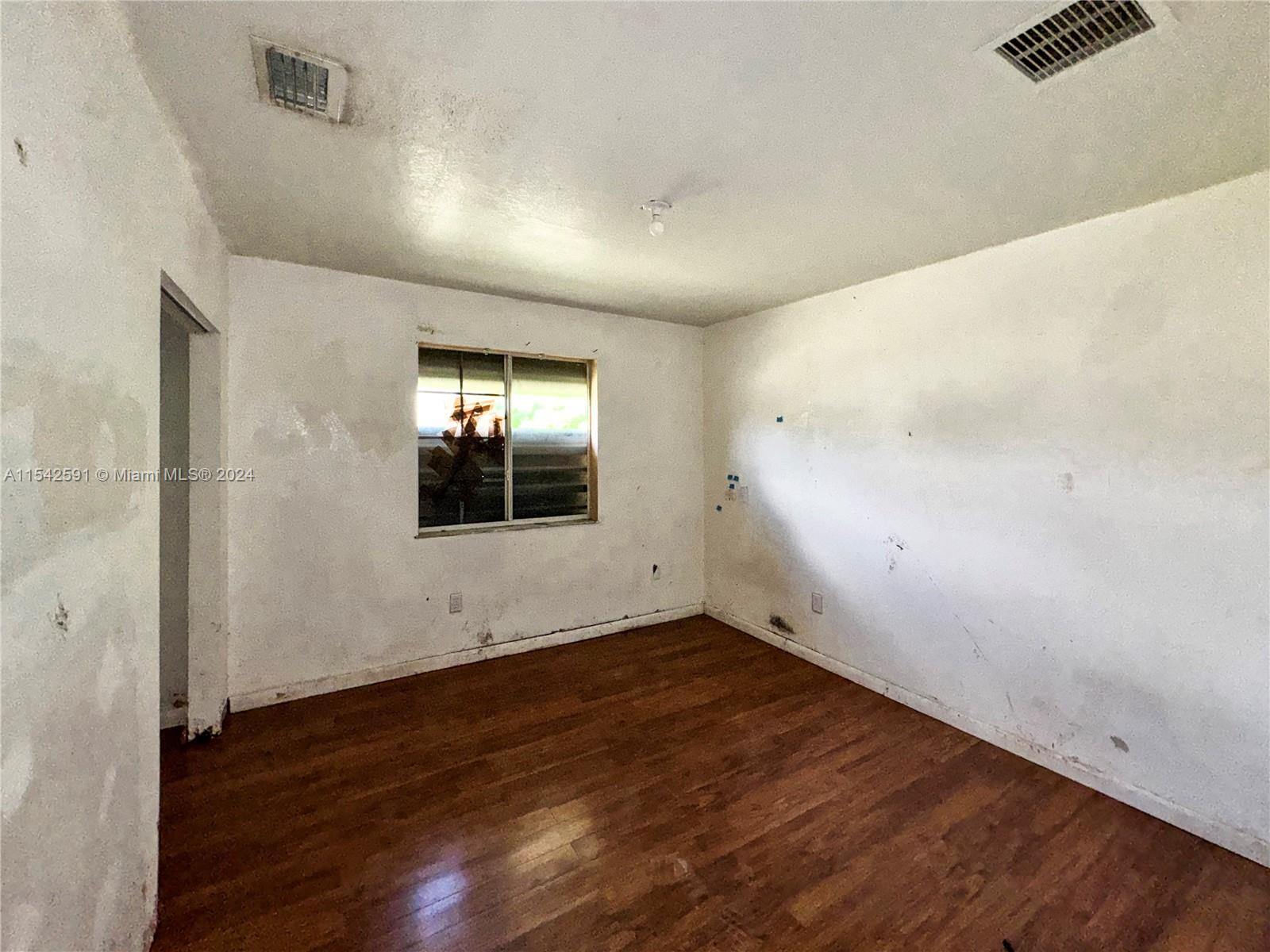 657 Southwest 7th Street Homestead, FL 33030 - Photo 20 of 33 an empty room with wooden floor and windows