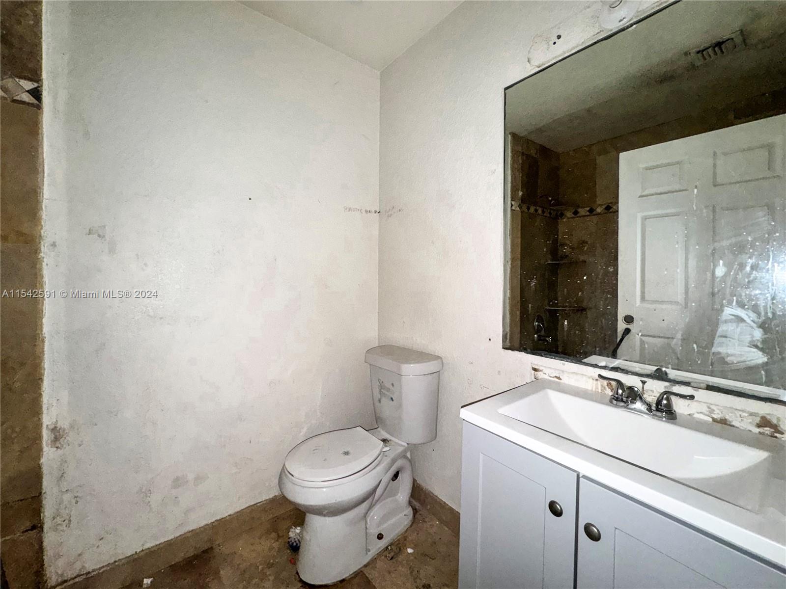 657 Southwest 7th Street Homestead, FL 33030 - Photo 23 of 33 a bathroom with a granite countertop sink a toilet and a mirror