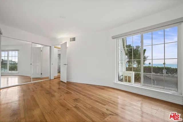 a view of empty room with wooden floor and fan