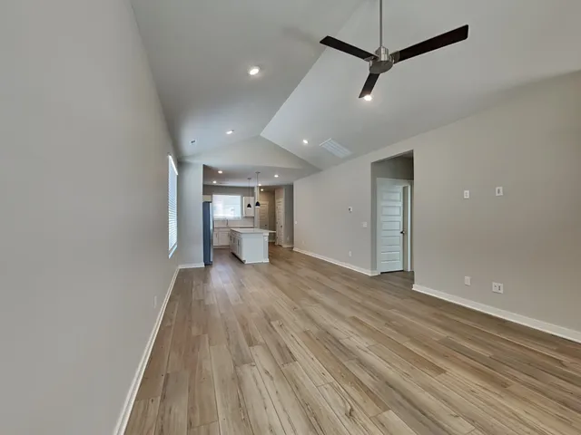 a view of a big room with wooden floor a ceiling fan and window