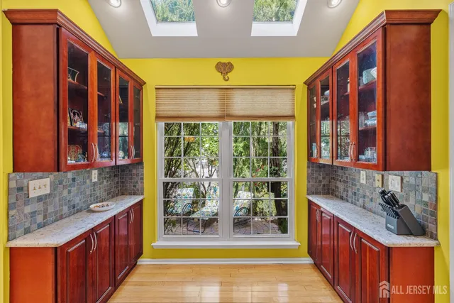 a kitchen with stainless steel appliances granite countertop a stove top oven a sink a dining table and chairs with wooden floor