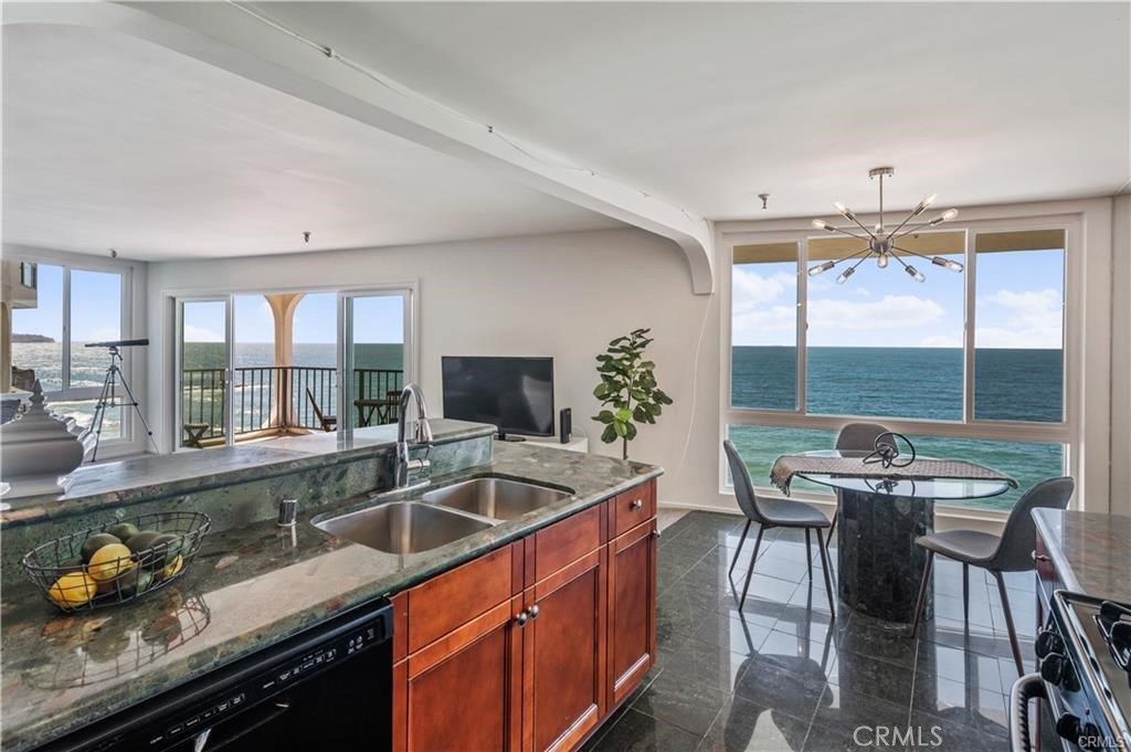 565 Esplanade, Unit 308 Redondo Beach, CA 90277 - Photo 9 of 28 a kitchen with granite countertop a sink a counter space dining table and stainless steel appliances