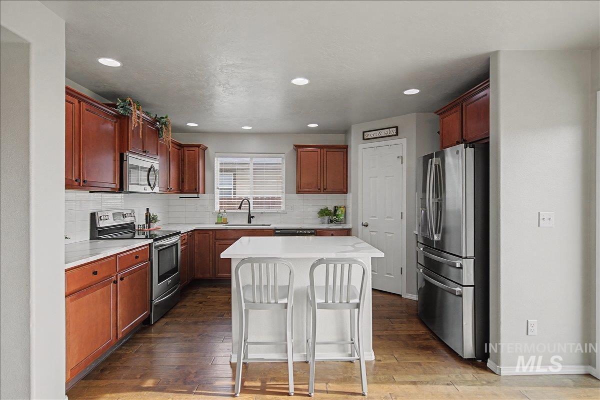 681 West Archerfield Street Meridian, ID 83646 - Photo 14 of 43 Kitchen with stainless steel appliances, a breakfast bar, dark wood-style flooring, a kitchen island, and recessed lighting