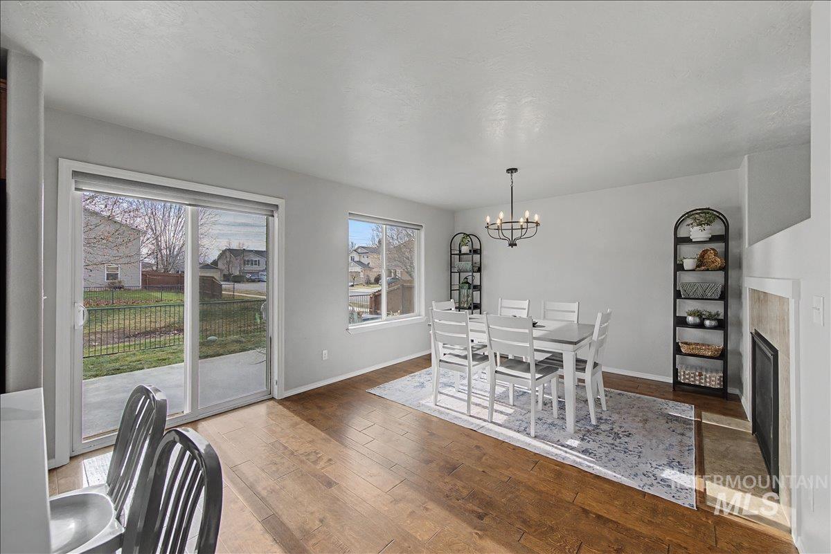 681 West Archerfield Street Meridian, ID 83646 - Photo 17 of 43 Dining area featuring a fireplace with flush hearth, hardwood / wood-style floors, and a chandelier
