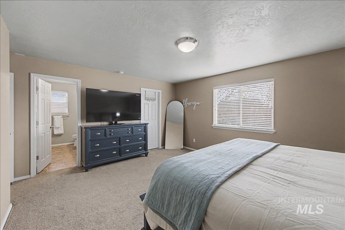 681 West Archerfield Street Meridian, ID 83646 - Photo 21 of 43 Bedroom featuring light colored carpet, a textured ceiling, and ensuite bath