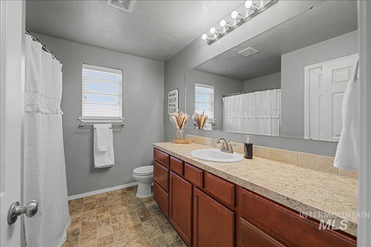681 West Archerfield Street Meridian, ID 83646 - Photo 23 of 43 Full bathroom with vanity, a shower with shower curtain, stone finish floors, and a textured ceiling