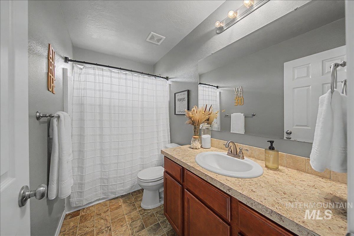 681 West Archerfield Street Meridian, ID 83646 - Photo 38 of 43 Bathroom with vanity, stone finish flooring, and a textured ceiling