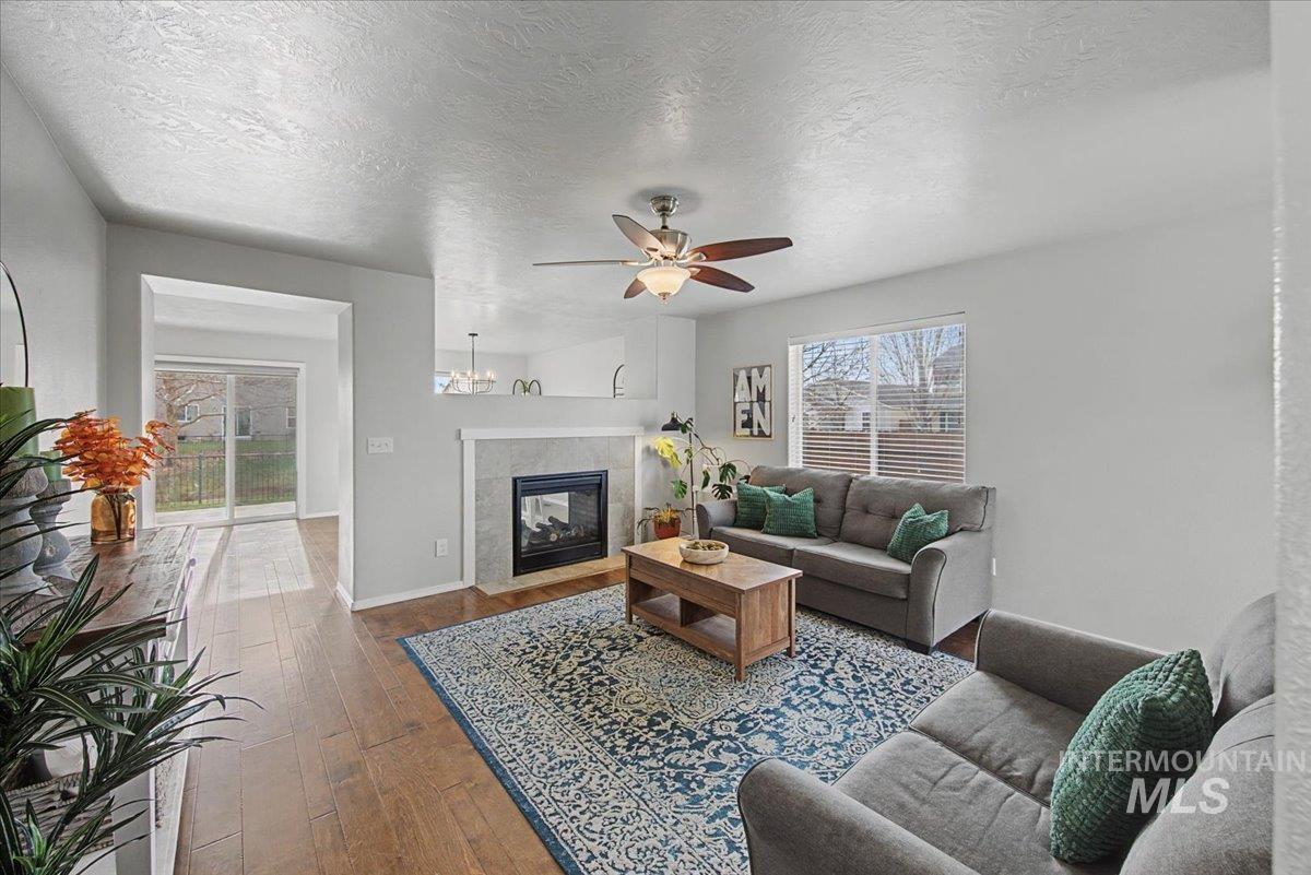 681 West Archerfield Street Meridian, ID 83646 - Photo 7 of 43 Living area featuring a textured ceiling, wood-type flooring, a ceiling fan, and a tiled fireplace