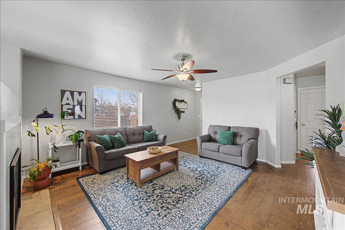 681 West Archerfield Street Meridian, ID 83646 - Photo 8 of 43 Living room with a fireplace, dark wood-style flooring, a textured ceiling, and a ceiling fan