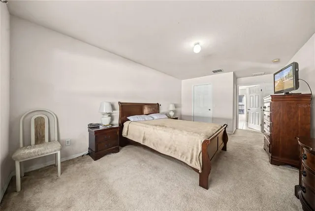 a bedroom with a bed chair and mirror