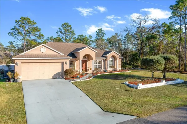 a view of a white house with a yard plants and a table and chairs