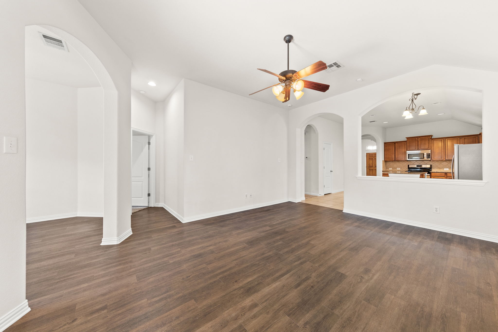 411 Tascate Street Georgetown, TX 78628 - Photo 41 of 41 An open floorplan seamlessly connects the well-lit living area to a functional kitchen with warm wood cabinetry.