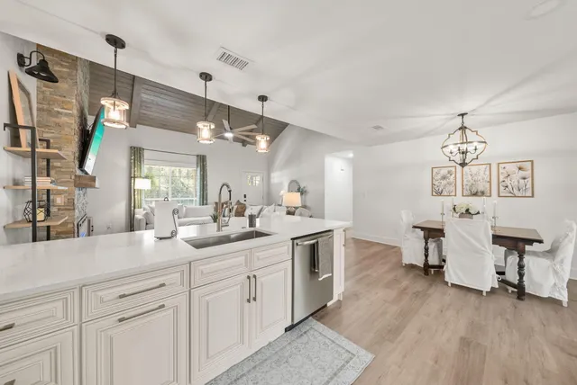 a open kitchen with a sink dishwasher a dining table and chairs with wooden floor
