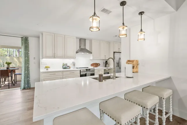 a kitchen with stainless steel appliances granite countertop a sink a stove a dining table and chairs with wooden floor