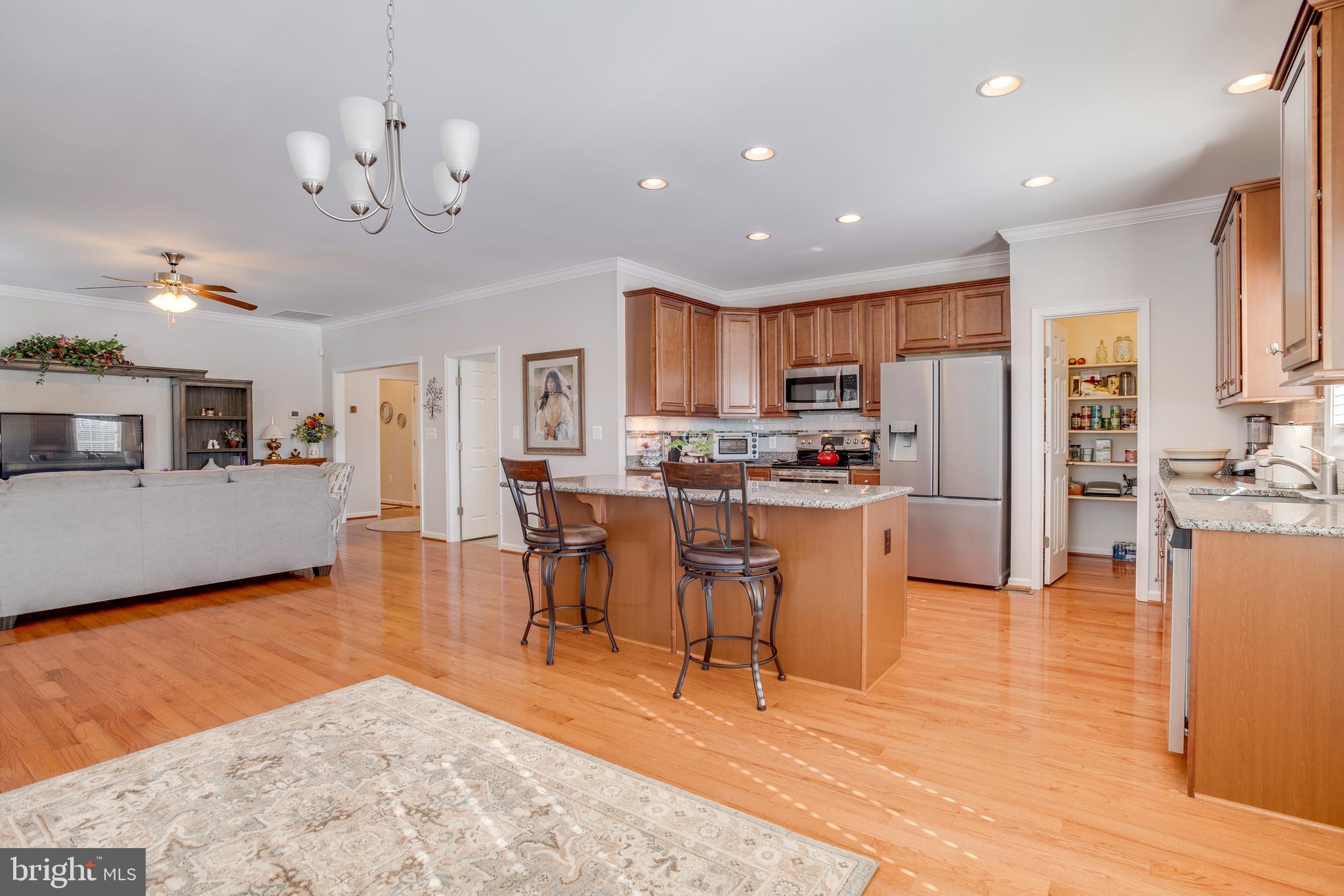 9408 Blackbird Loop Culpeper, VA 22701 - Photo 11 of 89 a kitchen with stainless steel appliances kitchen island granite countertop a refrigerator a stove a sink a dining table and chairs with wooden floor