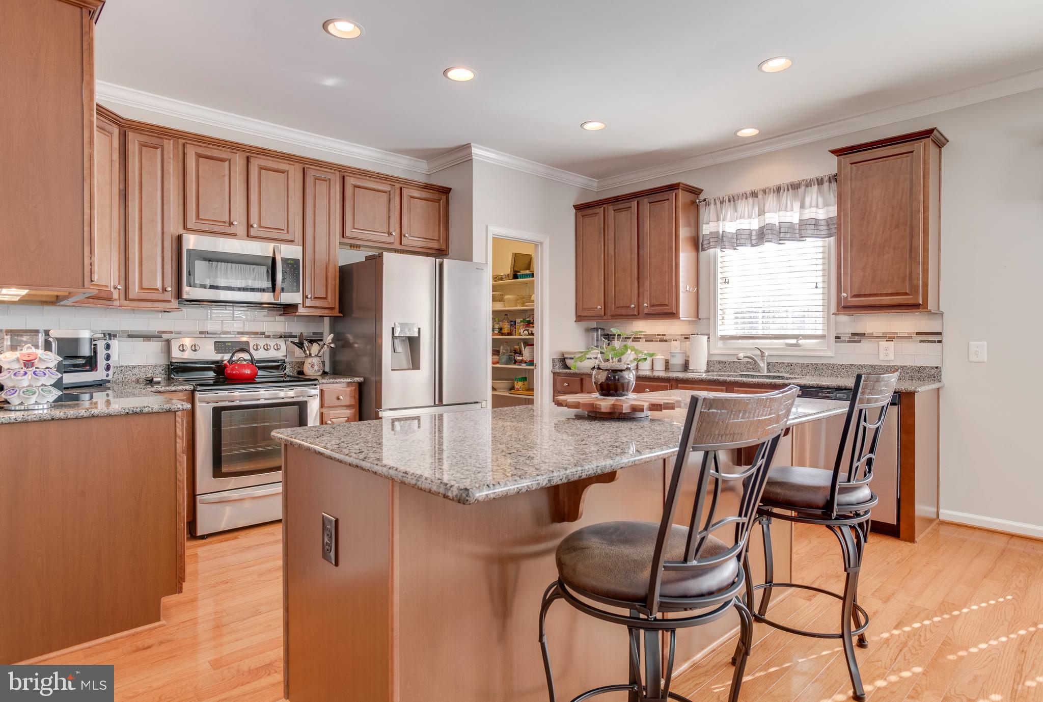 9408 Blackbird Loop Culpeper, VA 22701 - Photo 13 of 89 a kitchen with granite countertop a table chairs microwave and refrigerator