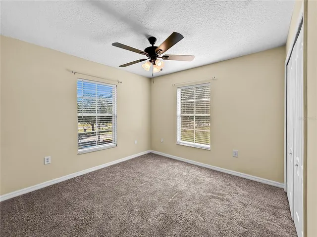 an empty room with windows and fan