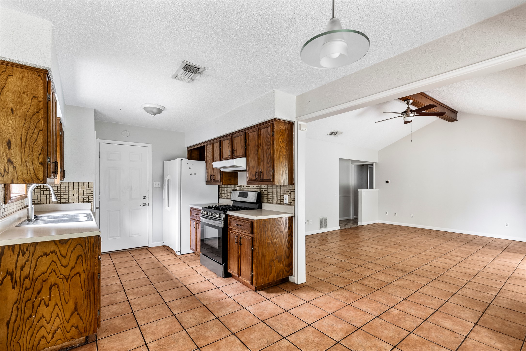 7506 Glenhill Road Austin, TX 78752 - Photo 5 of 24 A functional kitchen with wood cabinets flows seamlessly into an open living area with high vaulted ceilings.