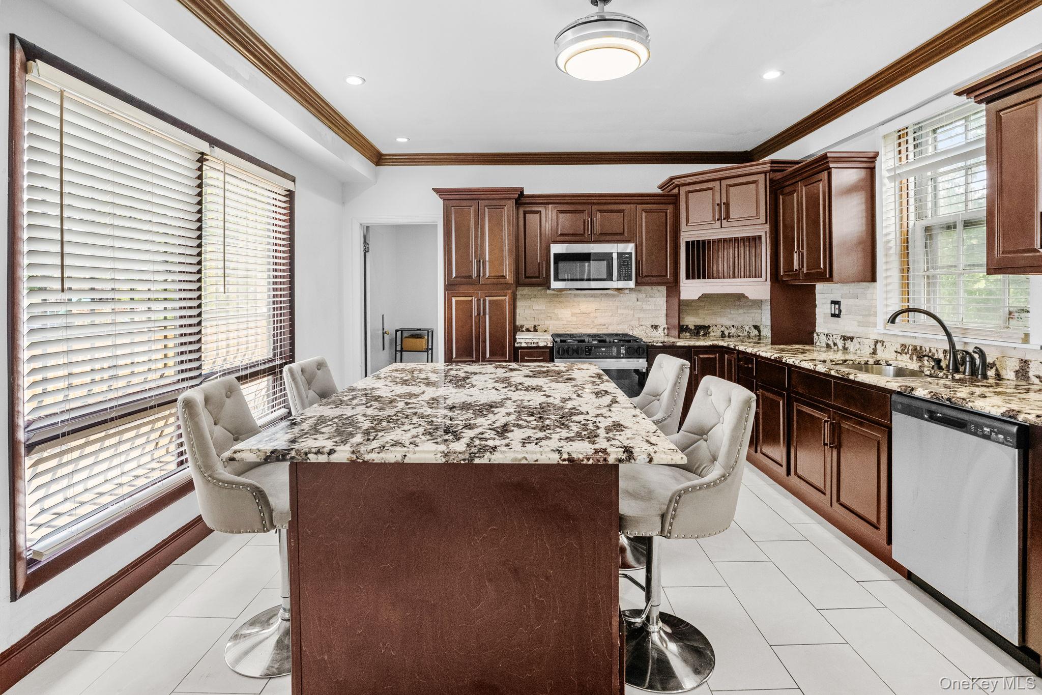 72 Hamilton Avenue New Rochelle, NY 10801 - Photo 9 of 28 a kitchen with kitchen island granite countertop a table chairs sink and cabinets