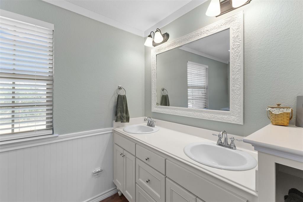 325 Bolton Road Granbury, TX 76049 - Photo 29 of 39 Double vanity with integrated sinks, white cabinetry, and a large decorative framed mirror