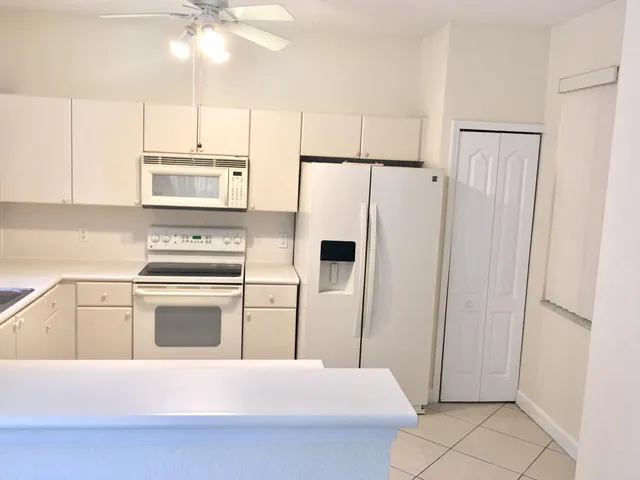a kitchen with stainless steel appliances a refrigerator a stove and white cabinets