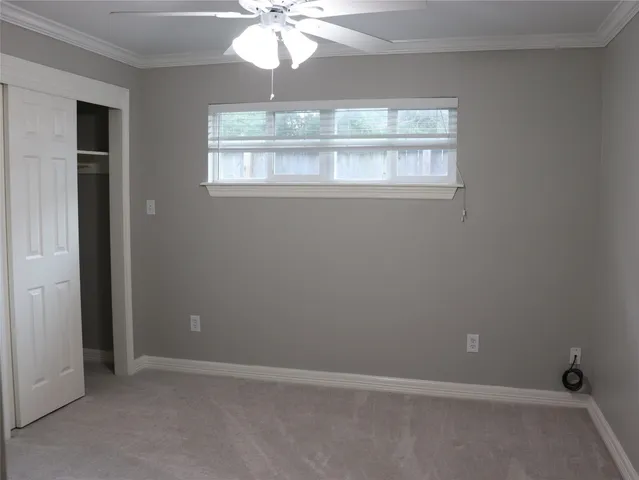 an empty room that has a chandelier fan and a window