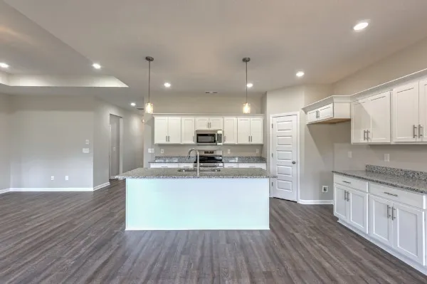 a open kitchen with stainless steel appliances granite countertop a refrigerator a sink dishwasher a stove and white cabinets with wooden floor