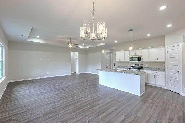 a large kitchen with kitchen island a sink dishwasher a refrigerator and white cabinets with wooden floor