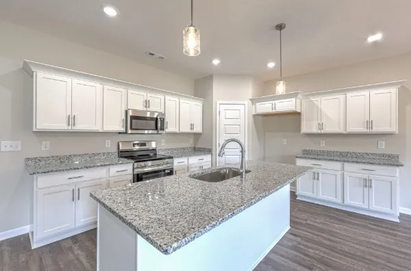 an open kitchen with white cabinets wooden floor and a kitchen island