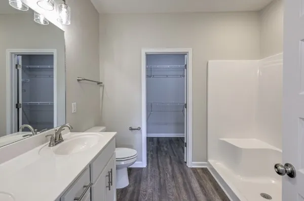 a spacious bathroom with double vanity a mirror and a shower