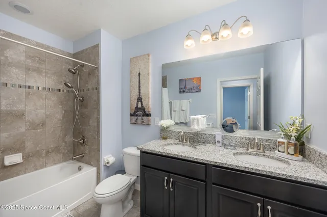 a bathroom with a granite countertop sink toilet a large mirror a bathtub and shower