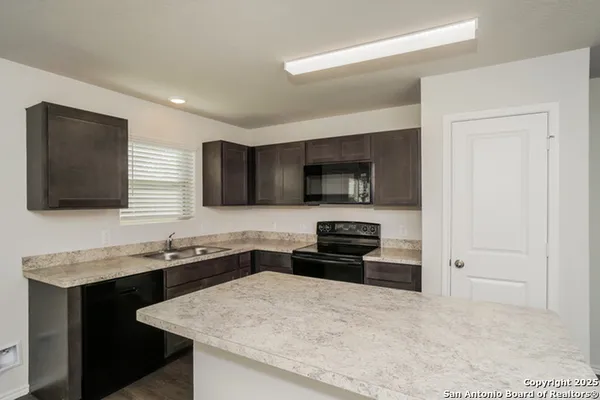 a kitchen with a sink and a stove top oven with wooden floor