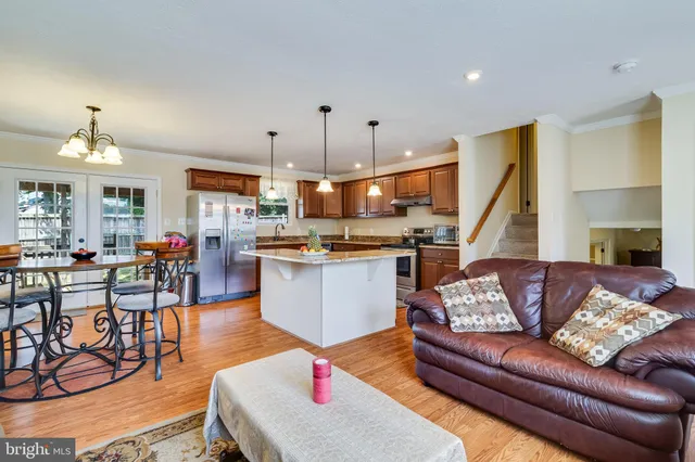 a living room with furniture kitchen view and a wooden floor