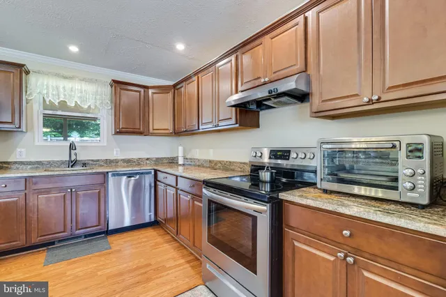 a kitchen with granite countertop wooden cabinets stainless steel appliances and a window