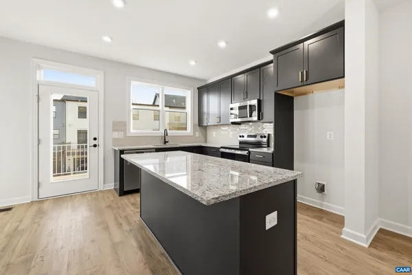 a kitchen with granite countertop stainless steel appliances a sink stove and refrigerator