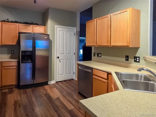 a kitchen with stainless steel appliances granite countertop a refrigerator a sink dishwasher and wooden cabinets with wooden floor