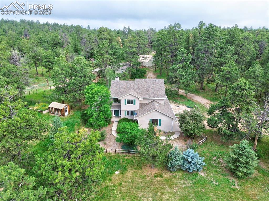 an aerial view of a house with yard and trees in the background