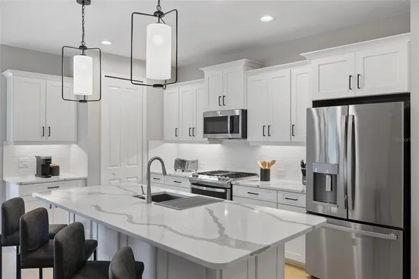 a kitchen with stainless steel appliances a refrigerator sink and microwave