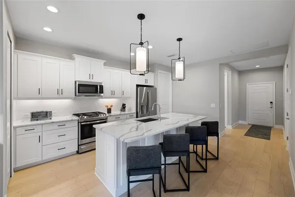 a kitchen that has a table chairs and stainless steel appliances