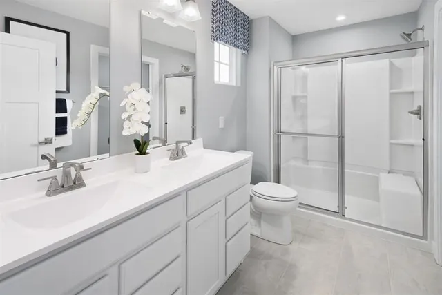a bathroom with a double vanity sink toilet and shower