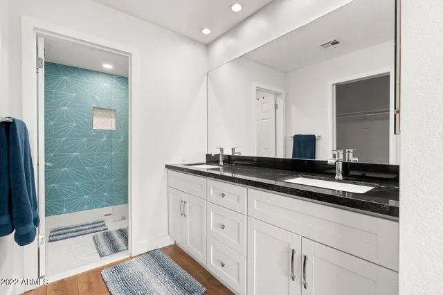 a bathroom with a granite countertop sink a mirror and a shower
