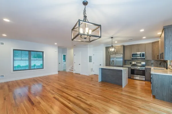 a view of a kitchen with stainless steel appliances granite countertop a refrigerator a stove top oven a sink dishwasher and wooden floor