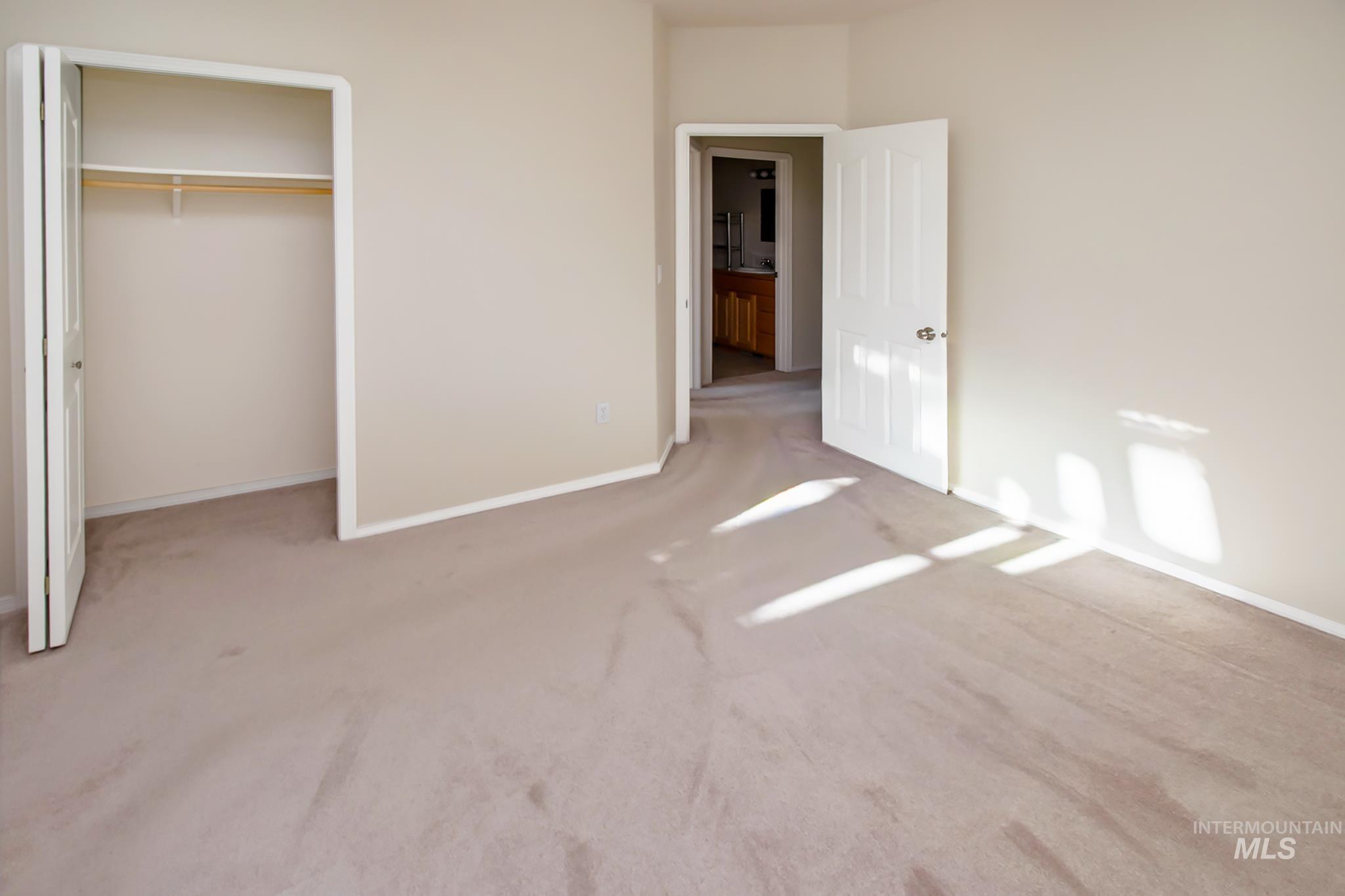 2133 13th Street Lewiston, ID 83501 - Photo 24 of 38 Neutral-toned interior room featuring wall-to-wall carpeting, a built-in closet with bi-fold doors, and a doorway leading to an additional space