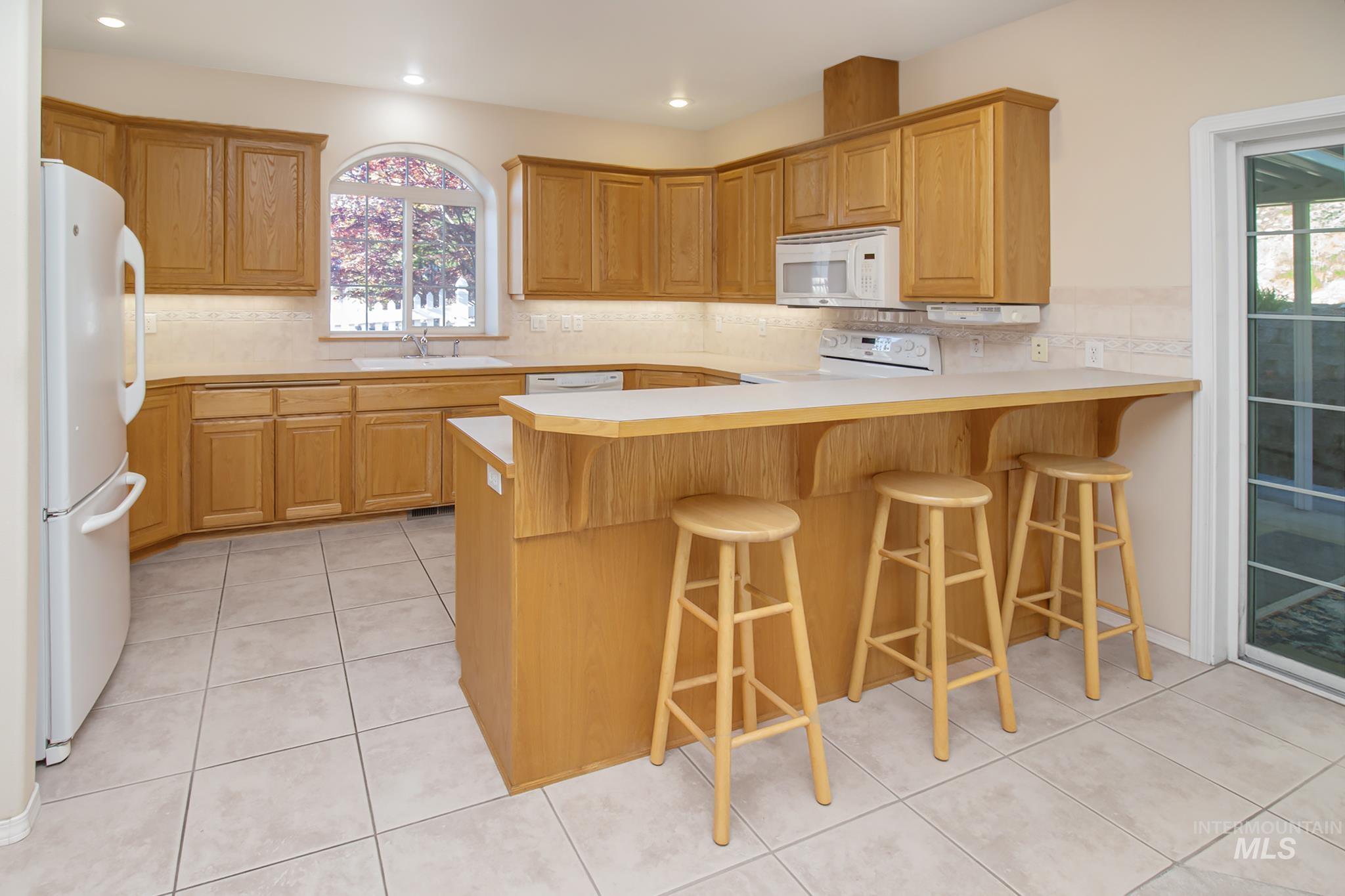 2133 13th Street Lewiston, ID 83501 - Photo 8 of 38 U-shaped kitchen featuring wood cabinetry, a breakfast bar, white countertops, tile flooring, and a sliding glass door