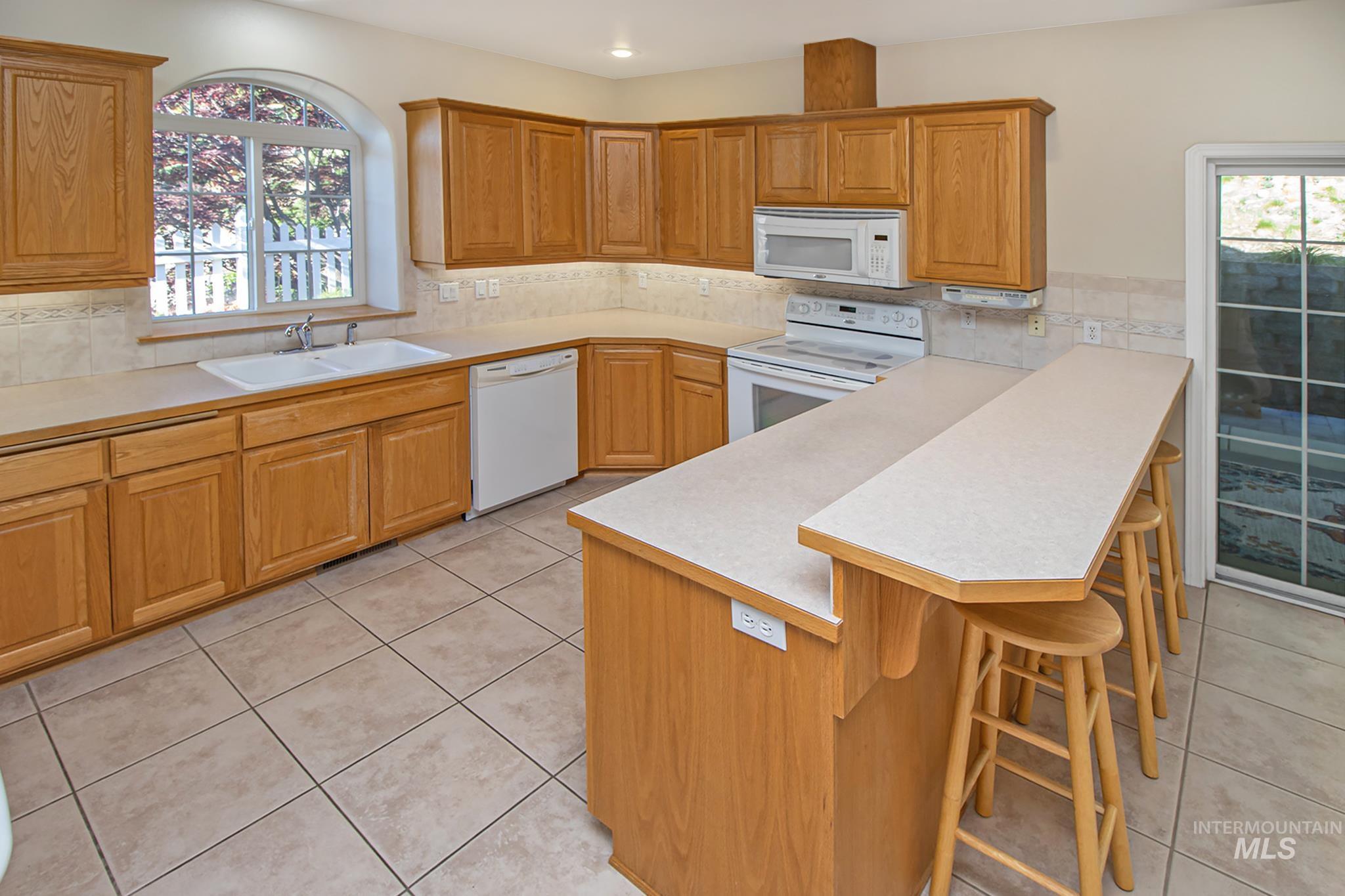 2133 13th Street Lewiston, ID 83501 - Photo 9 of 38 Kitchen featuring wood-finish cabinetry, tile flooring, a double basin sink, and a breakfast bar