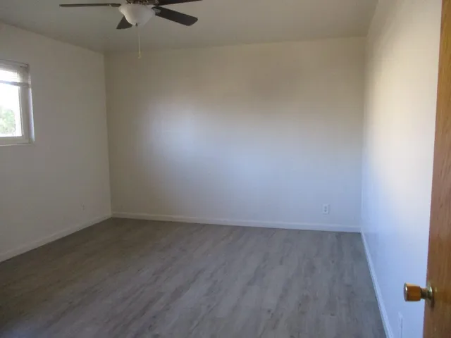 an empty room with a wooden floor and windows