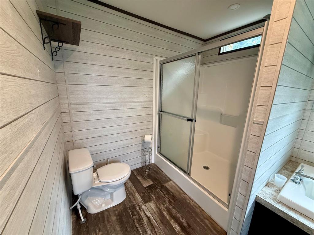 145 Adalida Lane Springtown, TX 76082 - Photo 16 of 29 Bathroom featuring a shower with sliding glass doors, white toilet, and wood-finish flooring