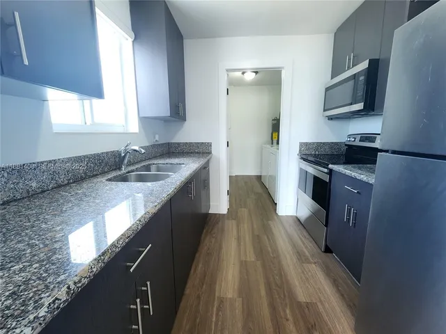 a kitchen with granite countertop a sink stove and refrigerator