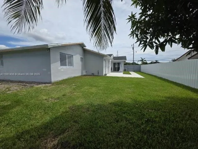 a view of a backyard with plants and palm trees