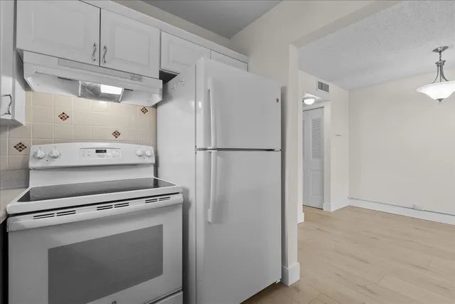 a white refrigerator freezer and a wooden floor